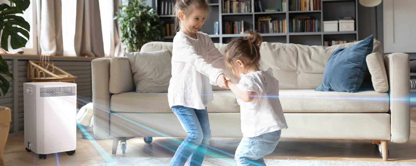 Two young children dancing and playing in a bright living room with an Inova air purifier circulating clean air in the background