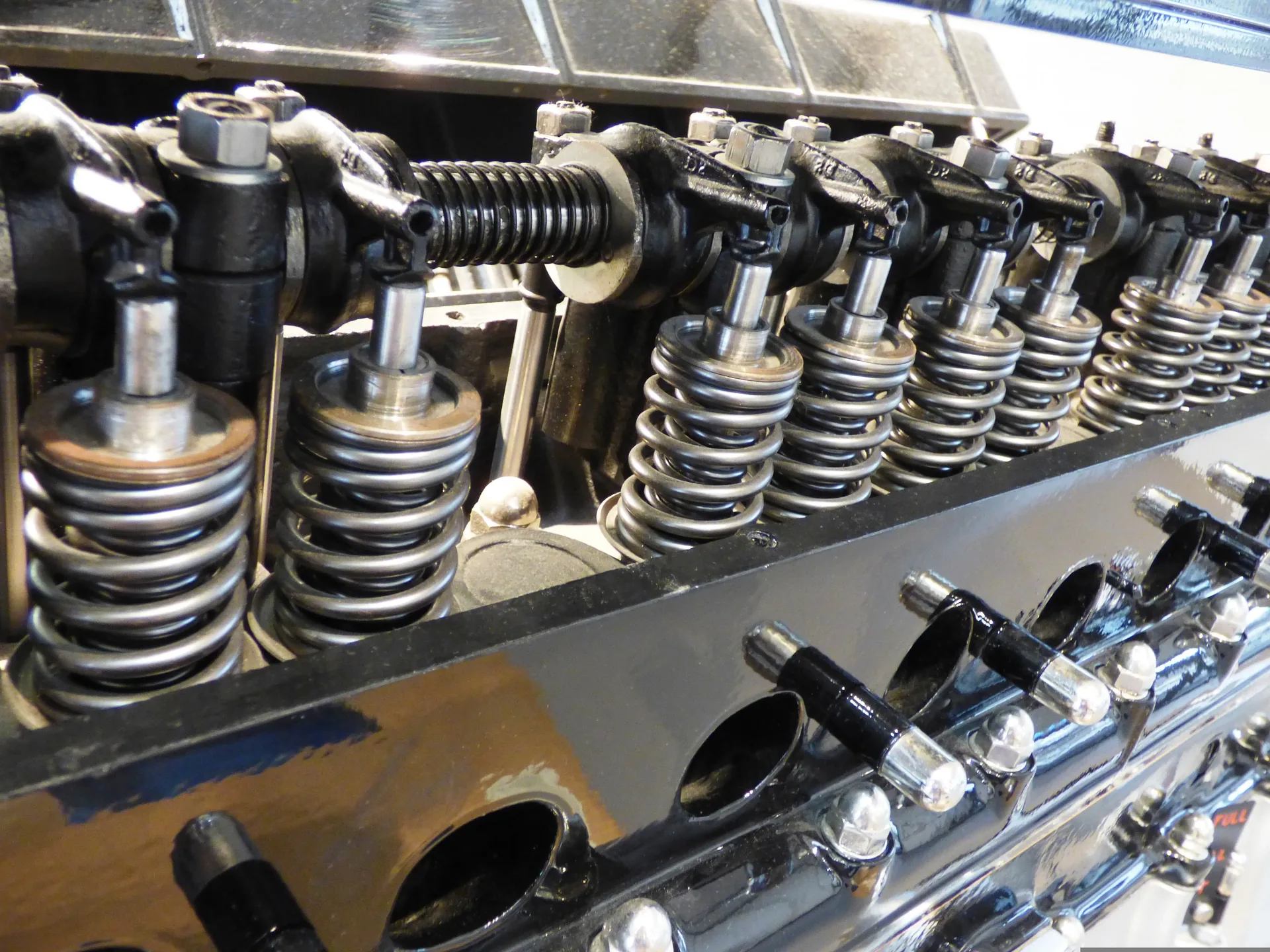 Close-up of a vintage automotive engine showing polished valve springs, rocker arms, and chrome components